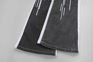Detail of dark grey washed denim leg openings with white contrast side stripes and print