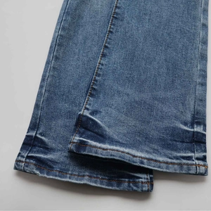 Macro shot of high-waist flare jeans with orange contrast stitching and retro washed finish