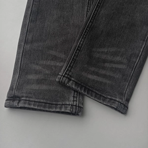 Detail of gray distressed denim hem with vintage washing and double-stitch craftsmanship