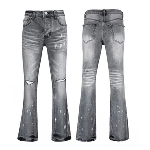 Detail view of grey washed flare jeans featuring distressed holes and white paint splatters