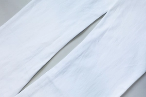 Detailed macro view of white denim fabric texture with thick twill pattern and durable stitching