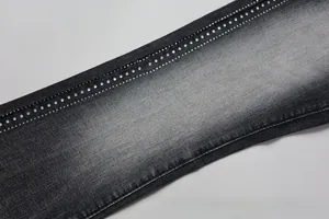 Macro detail of washed black denim fabric with double rows of silver rhinestones