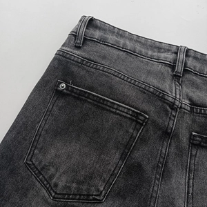 Macro shot of washed black-gray denim texture with metal rivet details on the back pocket