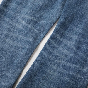 Close-up of blue flared denim jeans showing retro washed texture and twill fabric detail