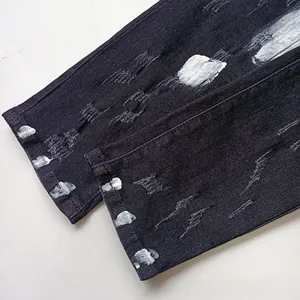 Detail of black washed jeans featuring distressed hems and silver spray paint finish