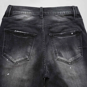 Vaqueros negros lavados con detalles de salpicaduras de pintura blanca y textura denim