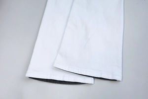 Detailed close-up of white denim hem with contrast lining and precision stitching finish