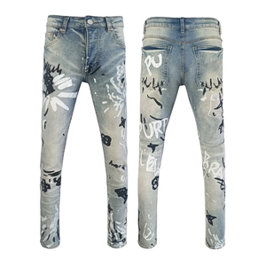 Detail of light blue washed slim jeans featuring white and black graffiti print accents