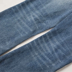 Macro shot of blue washed denim texture and distressed details on flared jeans