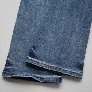 Detail shot of blue denim flared jeans showing double orange stitching and washed texture