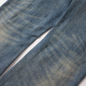 Detalle de vaqueros de campana de talle alto con textura denim lavado y tejido de sarga