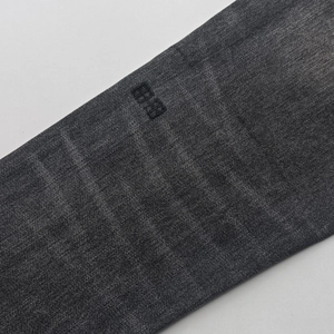 Detailed close-up of dark grey denim fabric with black embroidered pattern and twill texture