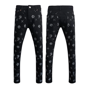 Close-up of black slim fit jeans featuring detailed white graffiti prints and star patterns