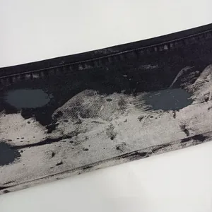 Dettaglio in primo piano del denim nero con macchie d'inchiostro grigie e bianche urbane