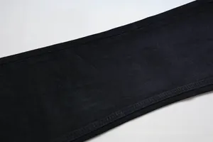 Detail von hochwertigem schwarzen Denim-Stoff mit präzisen Doppel-Ziernähten am Saum