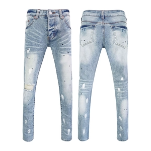 Detail of slim fit light blue jeans featuring hand-painted splatters and distressed rips