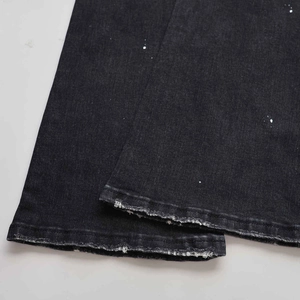 Detalle de dobladillo desgastado y manchas de pintura blanca en vaqueros denim negros