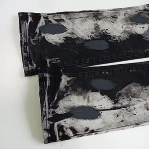 Dettaglio del fondo dei jeans grigio scuro lavati con stampa ovale e cuciture doppie