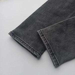 Detailed close-up of heavy dark grey denim jeans hem with neat double stitching
