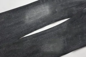 Macro shot of men's slim flared jeans with distressed denim texture and whiskers wash