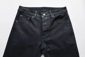 Makroaufnahme des schwarzen Denim-Bundes mit silbernem Metallknopf und Nieten