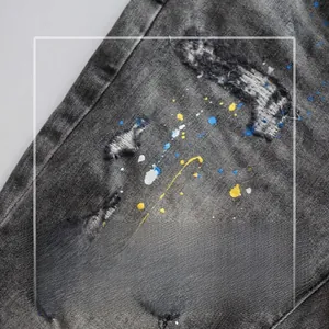 Detail of distressed grey washed denim fabric with colorful paint splashes and ripped texture