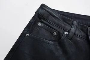 Detail der schwarzen Schlagjeans mit Bund, Metallnieten und strapazierfähiger Denim-Struktur