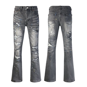 Detailed shot of grey washed flare jeans with distressed rips and colorful paint splatters