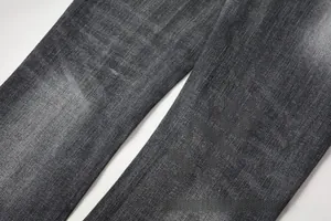 Macro detail of dark grey denim texture with washed distressed finish on flared jeans