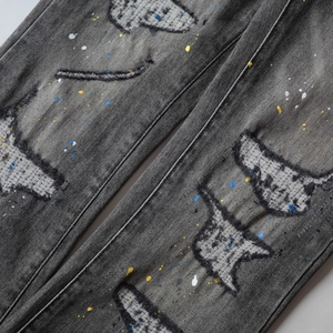 Close-up of distressed denim with colorful paint splatters and frayed patch details