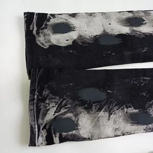 Dettaglio del denim grigio scuro con lavaggio vintage e texture di inchiostro a spruzzo