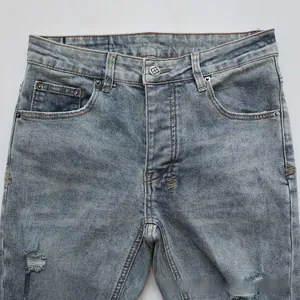 Detailed macro view of light blue washed denim with orange W embroidery and distressed holes