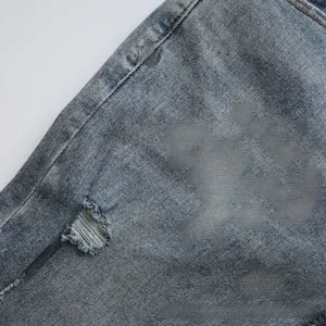 Macro view of blue-grey denim with yellow embroidery and hand-made distressed details