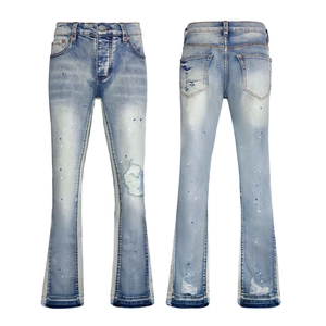 Detail view of light blue flared jeans featuring paint splatters and distressed ripped denim