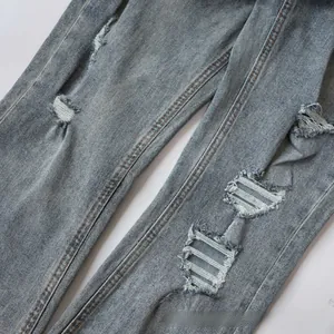 Detail of distressed light blue denim jeans with white frayed rips and vintage whiskers
