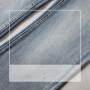 Détail du tissu denim délavé bleu clair montrant l'armure sergée et les coutures élastiques