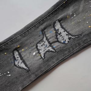 Macro view of grey washed denim with colorful paint splatters and distressed patches