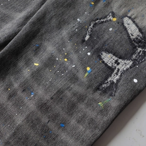 Close-up of ripped denim with colorful paint splatter and vintage washed texture