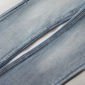 Gros plan détaillé du tissu denim délavé bleu clair avec texture sergée et double couture