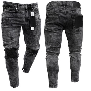 Detailed macro view of distressed knee holes and ankle metal zippers on slim fit jeans