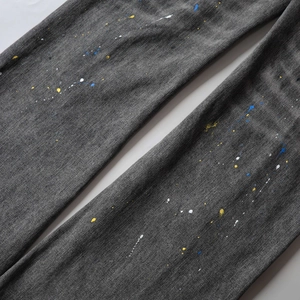 Detail view of grey washed denim fabric with vibrant colorful paint splatter patterns