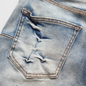Macro view of blue denim back pocket with orange contrast stitching and faded wash texture