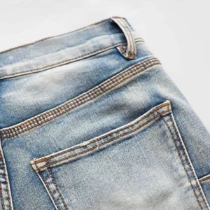 Detail of light blue denim jeans showing stitching, back pocket, and belt loops