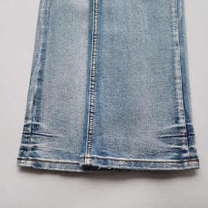 Détail de l'ouverture de jambe en jean bleu délavé avec ourlet à double couture