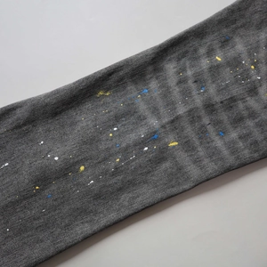 Macro detail of dark grey denim fabric with artistic colorful paint splatter texture