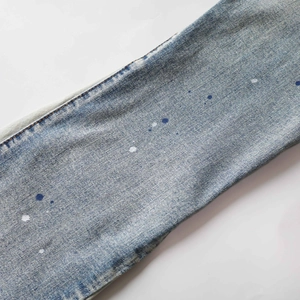 Macro detail of light blue washed denim fabric with unique artistic white dot splatter pattern