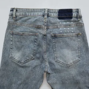 Detailed view of light blue flare jeans featuring white cross embroidery on back pocket