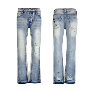 Detailed view of light blue washed denim flare pants with paint splatter and distressed holes