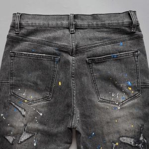 Macro detail of men's distressed grey flare jeans with paint splatters and worn finish