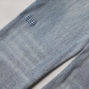 Gros plan sur le denim délavé bleu clair avec broderie carrée et texture sergé